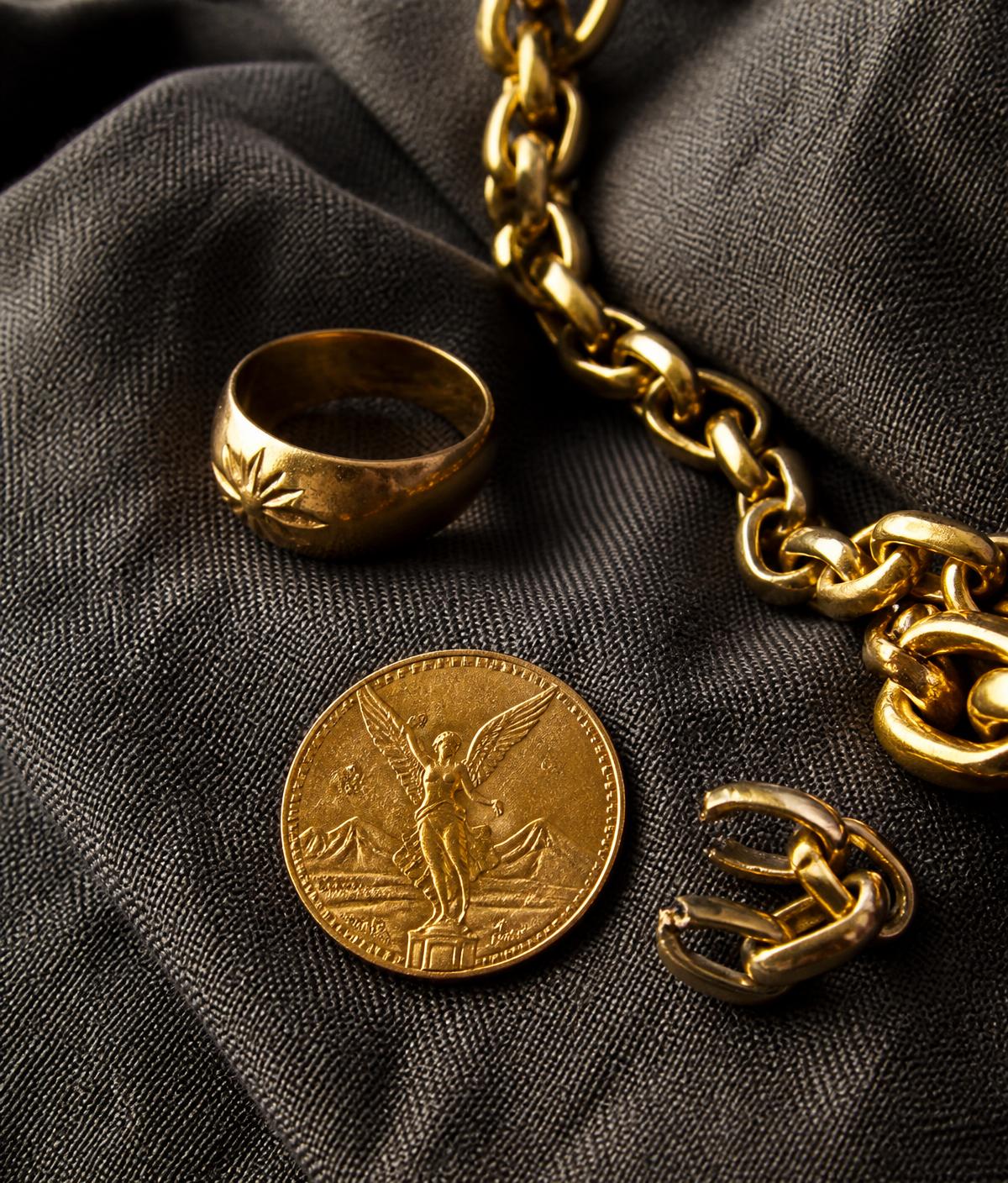 Gold ring, chain and Centenario coin on charcoal linen